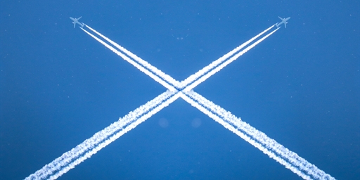 blue sky with aeroplane condense trails in the shape of an X