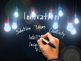 Innovation related words with lightbulbs and a human hand on black backgroundeadon a blackboard