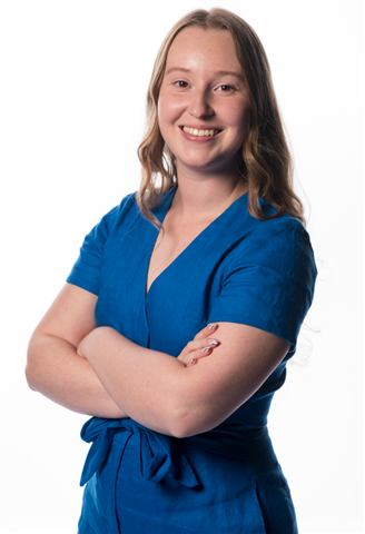 A person in a blue dress with her arms crossed