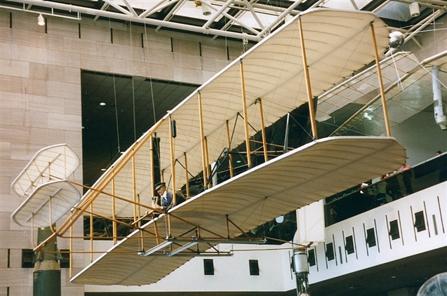 An old fashioned aeroplane hanging from the roof of a museum