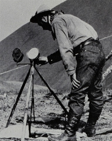 Image is in the public domain and shows the use of a Mance heliograph on the Alaska-Canada border, 1910.